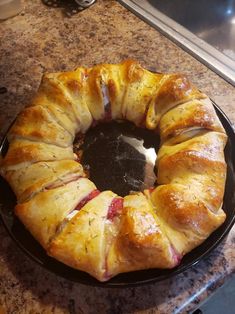 a croissant sitting on top of a black plate next to a stovetop