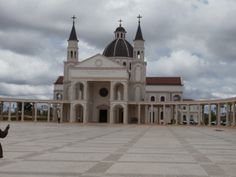 a woman is taking a photo in front of a large white building with two towers