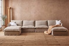 a living room with wooden floors and a large sectional couch in the middle of it