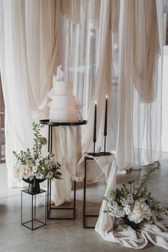 Large vegan three tier wedding cake with black taper candles and other decor with white wedding drapes and flowers Black Wedding Cake With White Flowers, Monochromatic Wedding Reception, Wedding Flower Colour Schemes, Black White And Beige Wedding Decor, Modern Black And White Wedding Decor Ceremony, Modern Cake Table Wedding, Black White And Ivory Wedding, Black And Crème Wedding, Wedding Backdrop Black And White