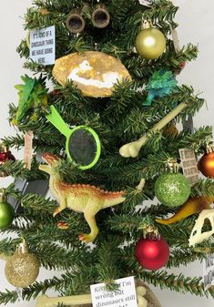 a christmas tree decorated with dinosaur ornaments and other holiday decorations, including a magnifying glass ornament