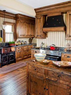 a large kitchen with wooden cabinets and black stove top oven in the center, surrounded by wood flooring