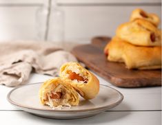 two pastries sitting on top of a white plate next to a wooden cutting board