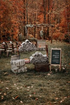 an outdoor ceremony setup with chairs and signs in the grass, surrounded by fall foliage