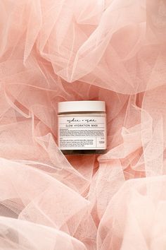 a jar of cream sitting on top of a pink netted cloth covered in tulle