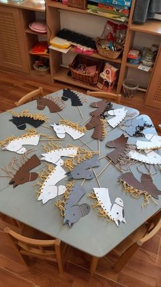 a wooden table topped with lots of cut out animals on it's sides next to a book shelf