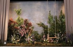 an image of a garden scene with flowers and plants on the stage set for a play