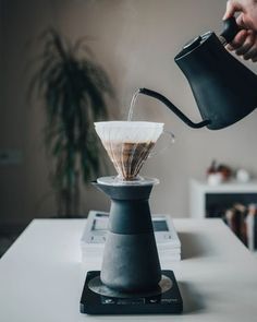 a person pours coffee into a cup on top of a stovetop burner