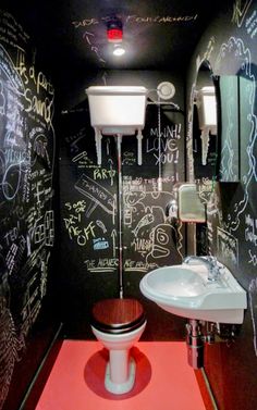 a bathroom with chalk writing on the walls and a toilet in the corner, along with a sink