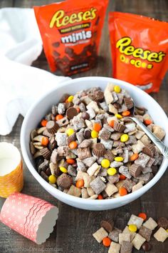 a bowl filled with cereal and candy next to two bags of reese's milk