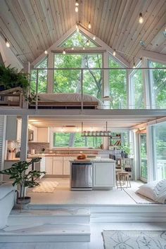 an open concept living room and kitchen area in a house with high ceilings, wood paneling, white walls, and floor to ceiling lighting