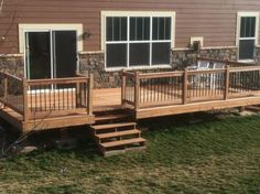 a wooden deck in front of a house with sliding glass doors and steps leading up to it