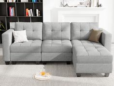 a gray sectional sofa sitting on top of a carpeted floor next to a book shelf