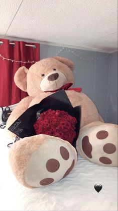 a large teddy bear sitting on top of a bed next to a bouquet of roses