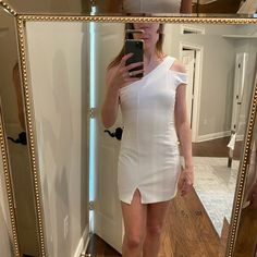 a woman taking a selfie in front of a mirror with her reflection wearing a white dress