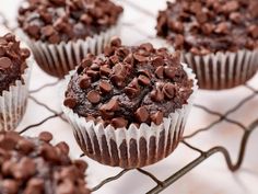 several chocolate cupcakes on a cooling rack with one muffin topped with chocolate chips