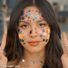 a woman with her hands up and painted on her face, posing for the camera