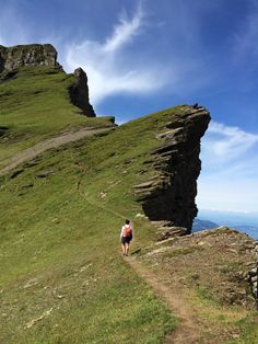 a man hiking up the side of a mountain with grass and rocks on both sides