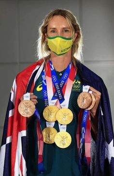 a woman wearing a face mask holding three gold medals