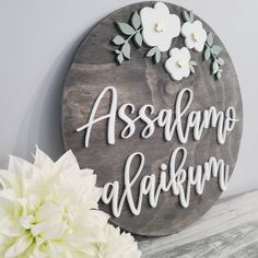 a wooden sign that says assanoo afakum next to a white flower