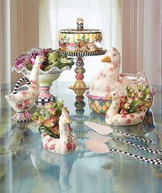 a table topped with vases filled with flowers and birds next to a cake stand