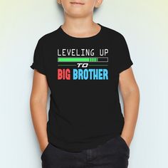 a young boy wearing a black tee shirt with the words leveling up and big brother on it