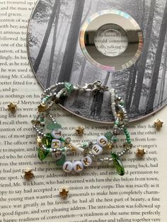 a cd sitting on top of a book next to a bracelet with beads and charms