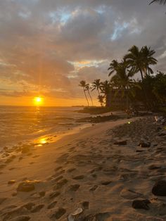 the sun is setting on the beach with palm trees