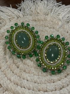 pair of green and white earrings sitting on top of a rug