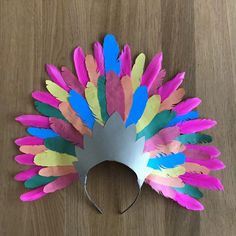 a metal headdress made out of colored feathers on a wooden table with scissors