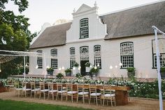 a large white house with tables and chairs set up for an outdoor wedding reception in front of it