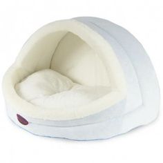 a white dog bed that is shaped like a dome with a cat sleeping inside it