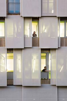 two people are looking out the windows of an apartment building with white walls and balconies