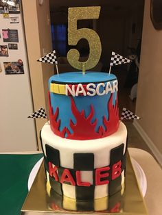 a birthday cake with the number five on top and race flags around it's edges