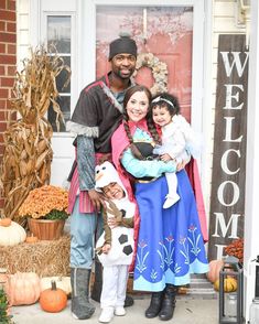 a man and two children standing in front of a door with pumpkins on the porch