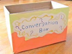 an open box with the words conversation box written in blue and yellow on it sitting on a wooden floor