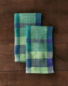 two green and blue checkered towels sitting on top of a wooden table