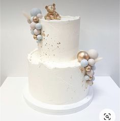 a three tiered white cake with gold and blue decorations