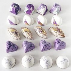 there are many different types of candies on the table with white and purple frosting