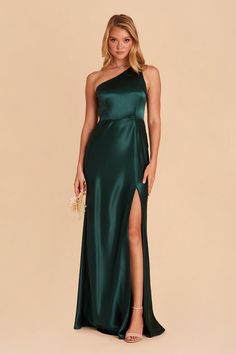 a woman in a long green dress with one shoulder and slit down the side, posing for