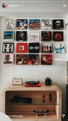 there are many pictures on the wall above this table and in front of it is a record player