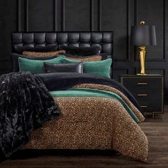 a leopard print comforter set on a bed with black headboard and foot board