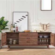 a wooden cabinet with wine glasses and bottles on it in front of a white wall