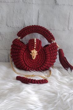 a crocheted purse with a tasseled handle on a white furnishing