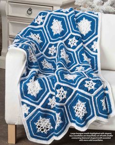 a blue and white crocheted afghan sitting on top of a couch