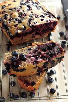 two slices of blueberry bread on a cooling rack next to some fresh blueberries