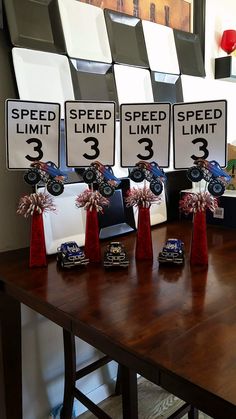 three speed limit signs are displayed on a table with red and white flowers in vases