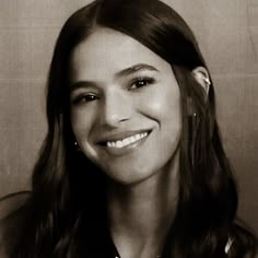 a black and white photo of a woman with long brown hair smiling at the camera