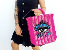 a woman holding a pink bag with an eye on it