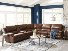 a living room with blue walls and brown leather couches in the middle of it